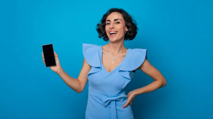 Kék ruhában lévő nő mutatja a mobiltelefonját